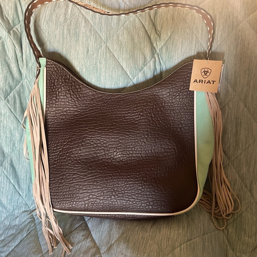 Ariat rich brown with baby blue side accents and ivory fringe. Tooled strap.